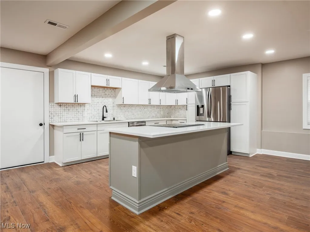 Kitchen with white cabinets, island exhaust hood, dark wood-type flooring, recessed lighting, and beamed ceiling