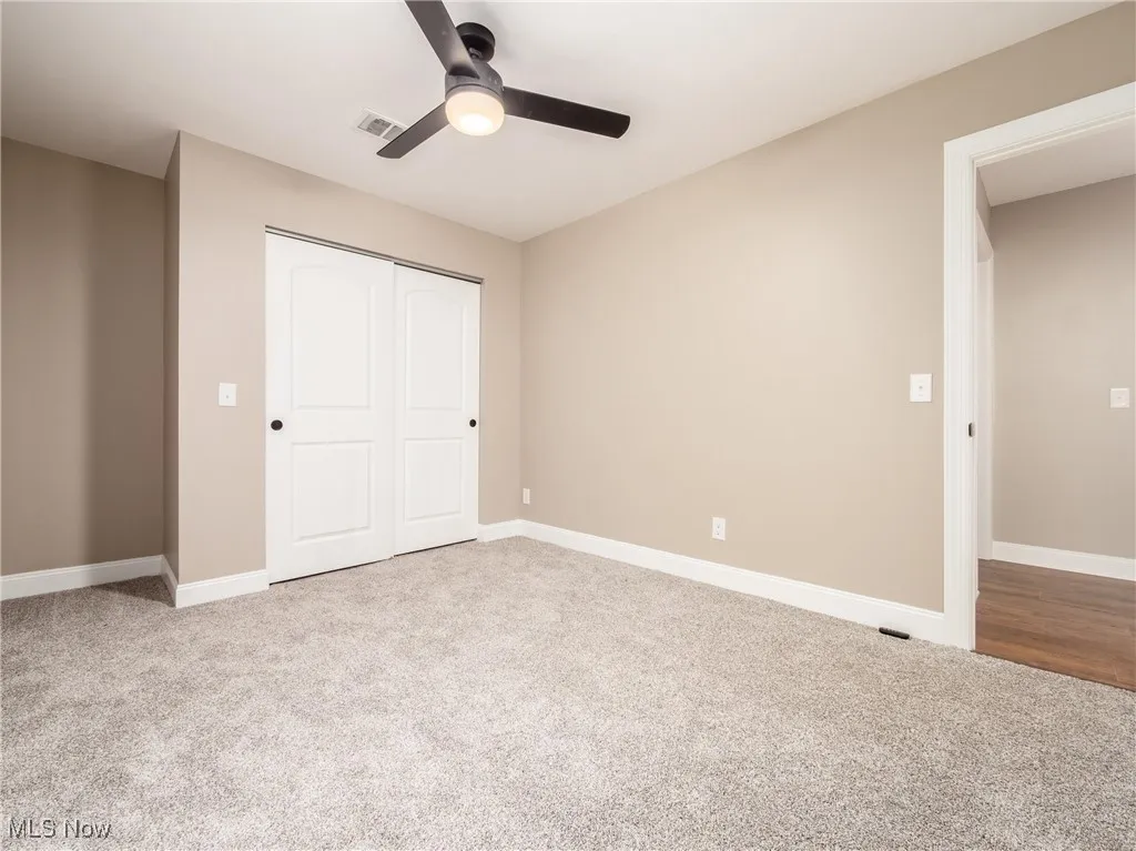 Unfurnished bedroom featuring light carpet, a closet, and ceiling fan
