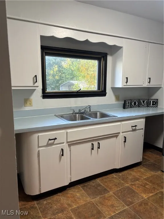 Kitchen with white cabinets, light countertops, and vinyl floors