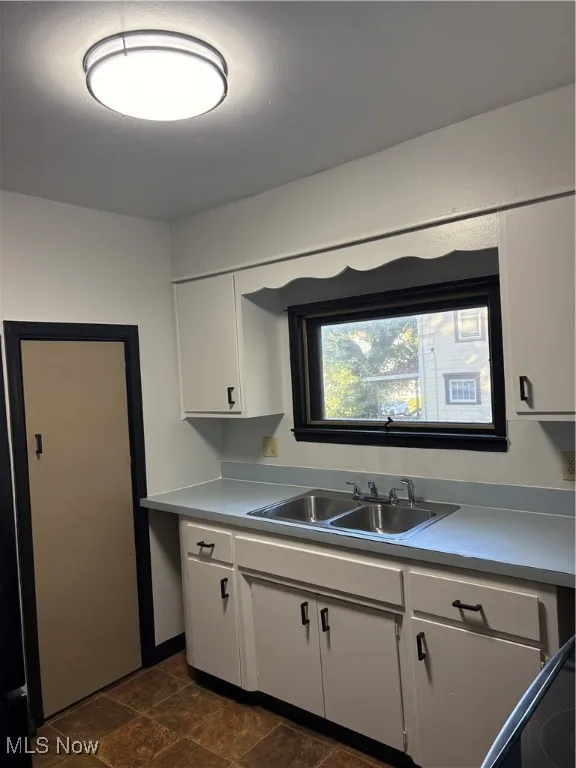 Kitchen with white cabinets, light countertops, dark stone finish vinyl floors, and range
