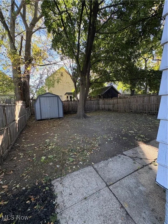 Fenced backyard featuring a storage unit