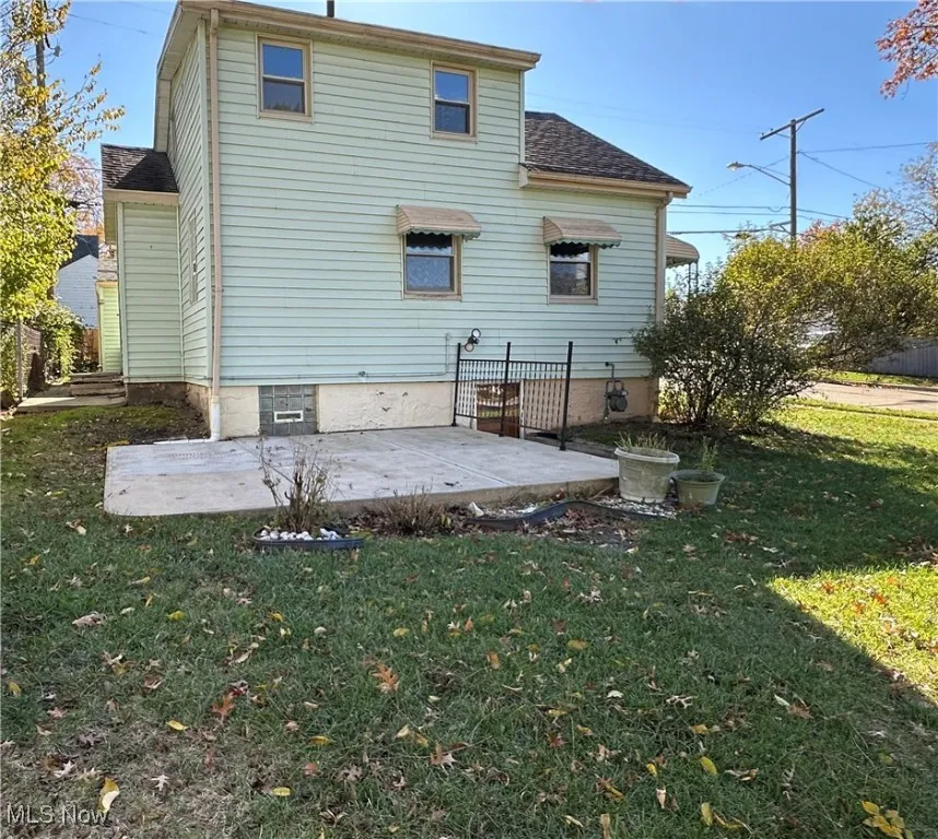 Rear view of property with a patio, a yard, and roof with shingles