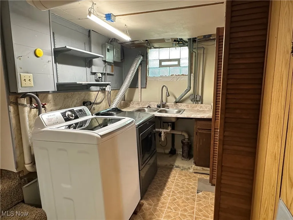 Kitchen with open shelves, light countertops, washer and dryer, light tile patterned floors, and electric panel