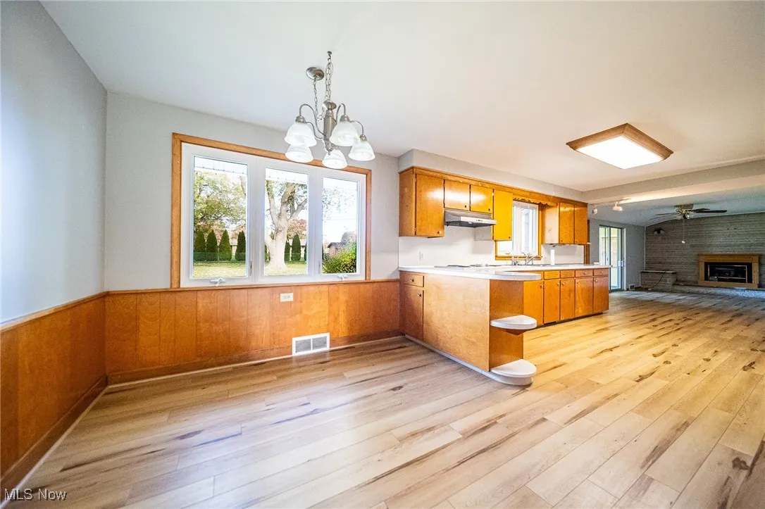 Kitchen featuring wood walls, open floor plan, wainscoting, a peninsula, and light countertops