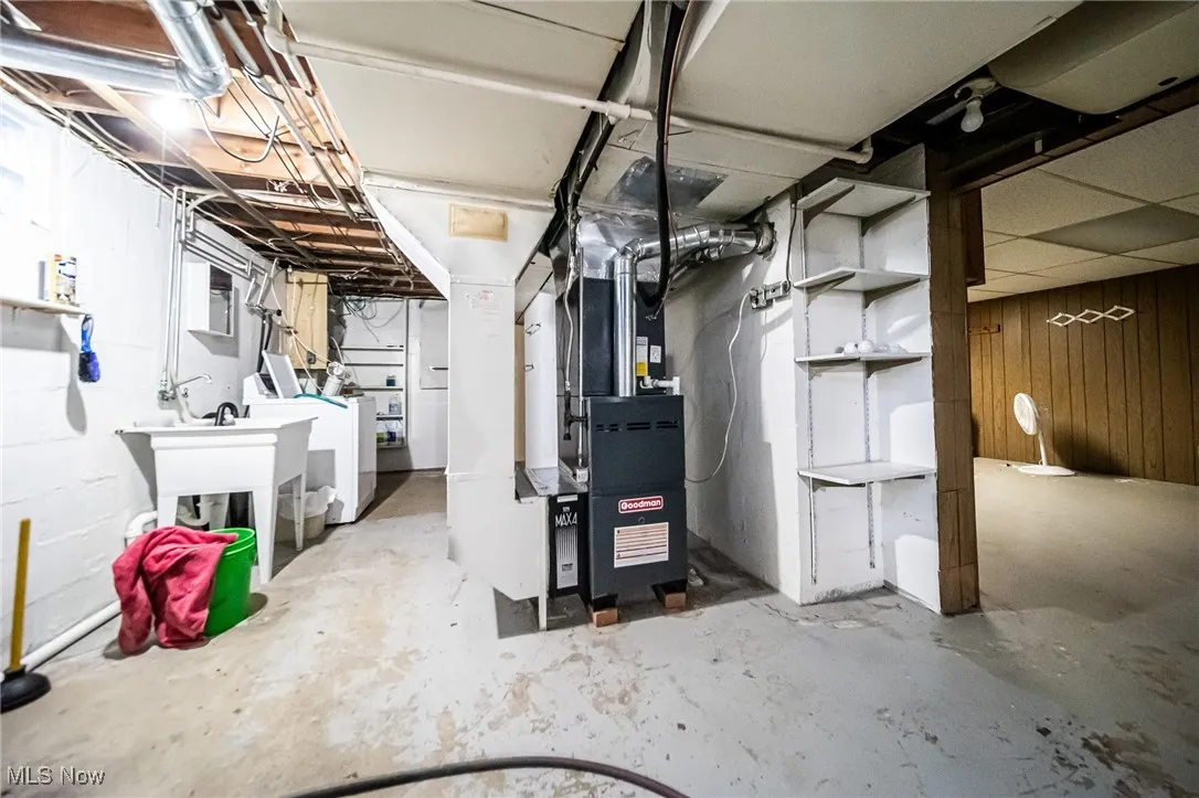 Unfinished basement featuring wooden walls and heating unit