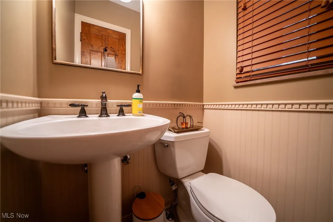 Half bath featuring a wainscoted wall and toilet