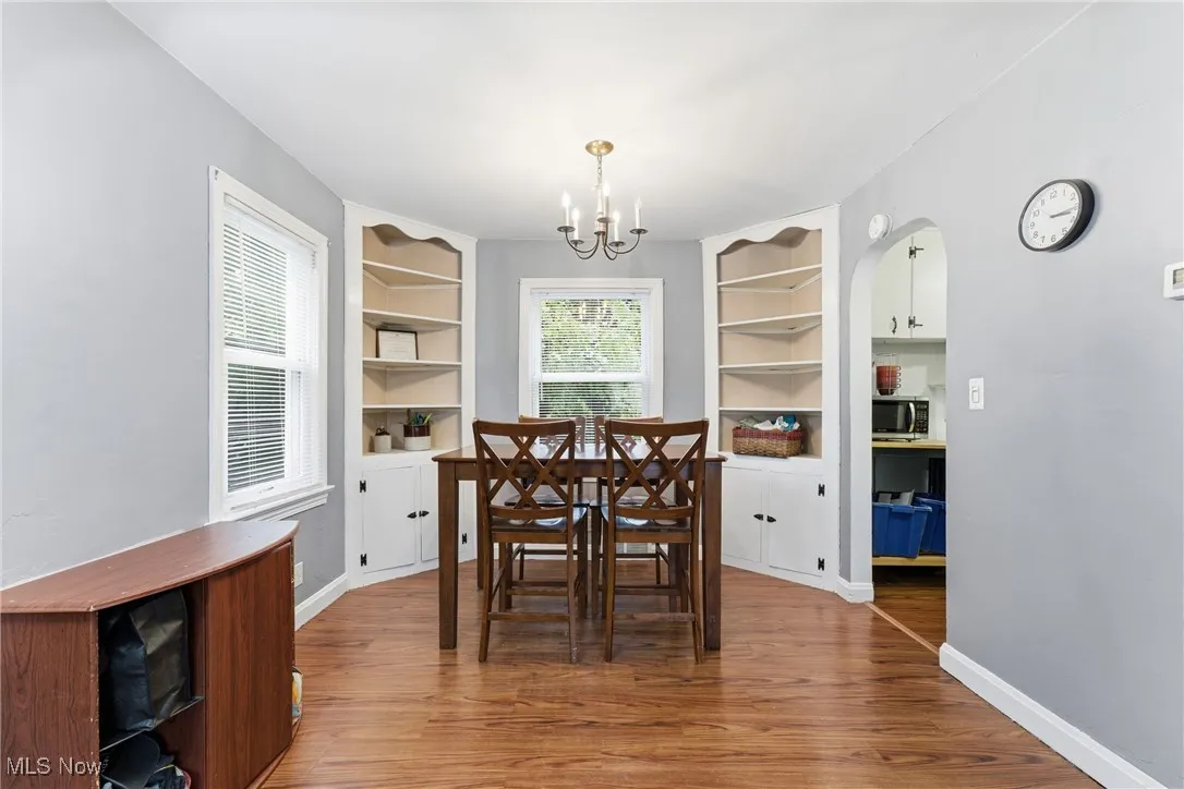 Dining space featuring light wood-style floors, a chandelier, built in shelves, and arched walkways