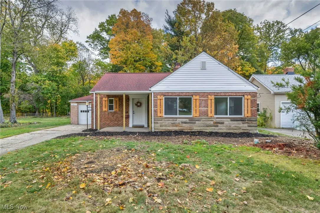 View of front of property featuring a front yard, a porch, brick siding, concrete driveway, and a garage