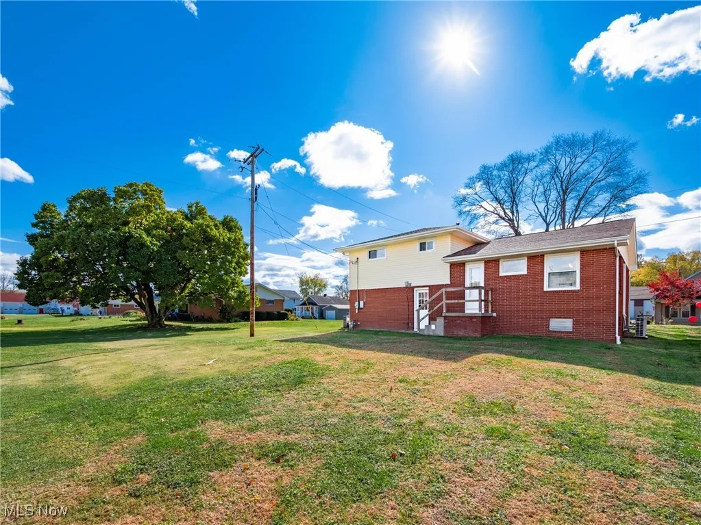Rear view of house with a yard and brick siding