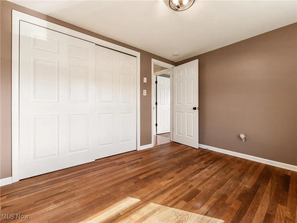 Unfurnished bedroom with wood finished floors and a closet