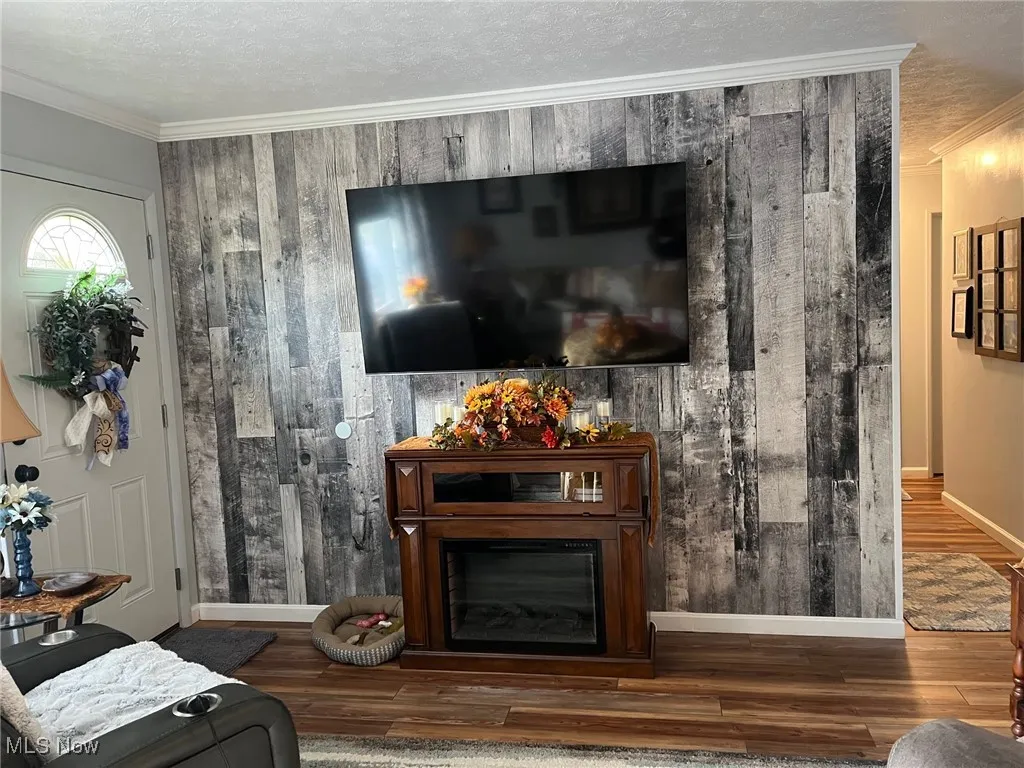 Living room featuring crown molding, a textured ceiling, and laminate floors