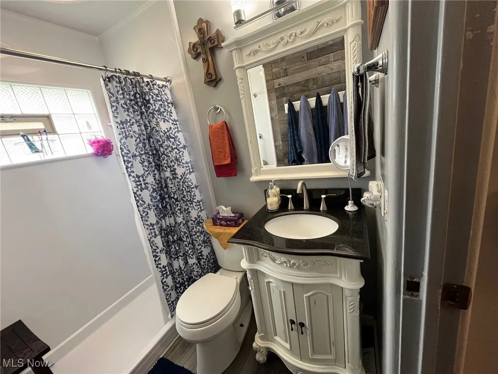 Full bath with vanity, curtained shower, and light fixtures