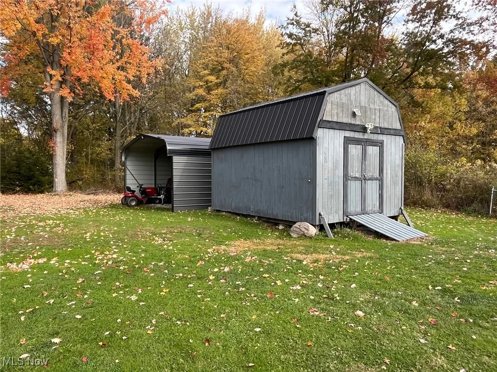 View of shed with view of wooded area and a detached carport used as storage