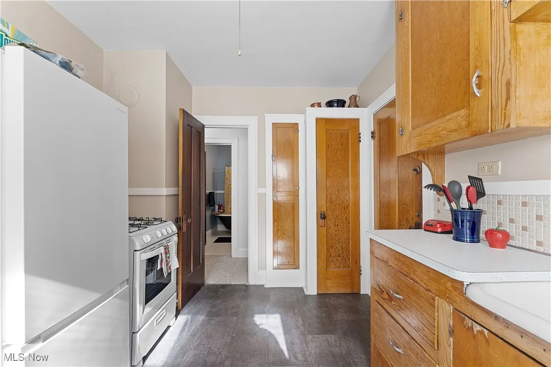 Kitchen featuring white appliances, light countertops, decorative backsplash, and brown cabinetry