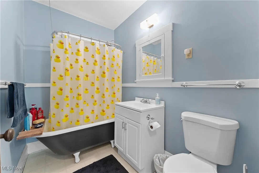 Bathroom with vanity, shower / bath combo with shower curtain, and light tile patterned floors