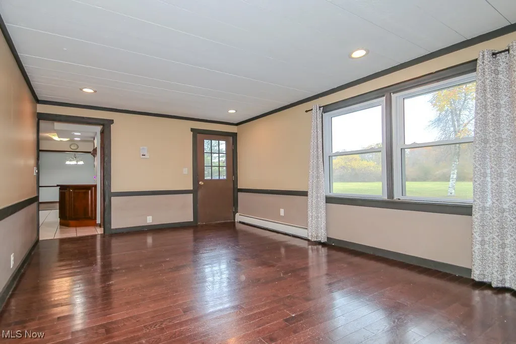 Unfurnished room with recessed lighting, dark wood-type flooring, ornamental molding, and a baseboard heating unit