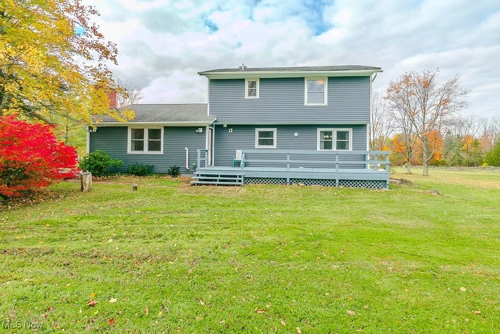 Back of house featuring a lawn and a deck