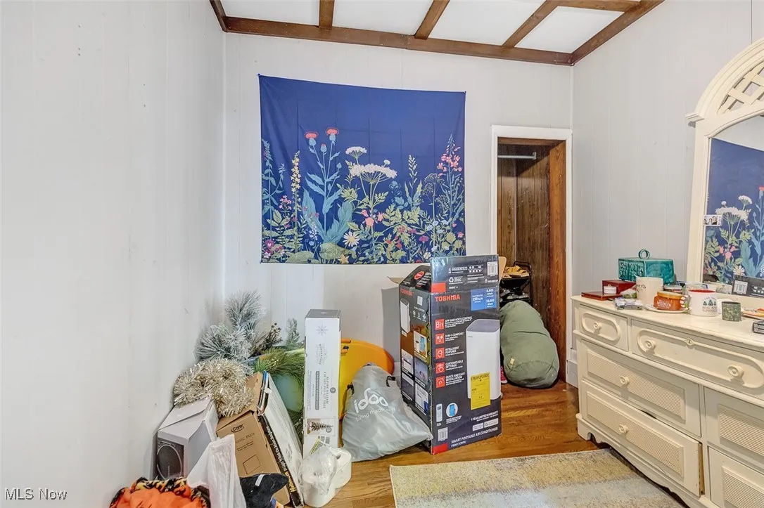 Bedroom with wood finished floors, wooden walls, and beam ceiling
