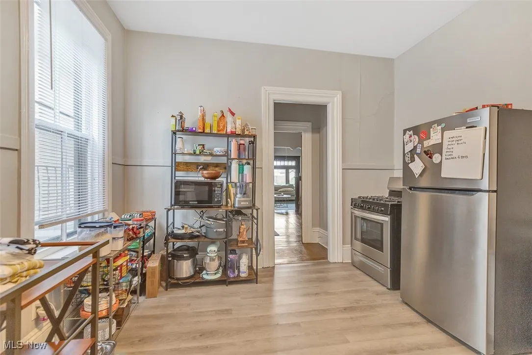 Kitchen with stainless steel appliances, healthy amount of natural light, light wood-style floors, and white cabinets
