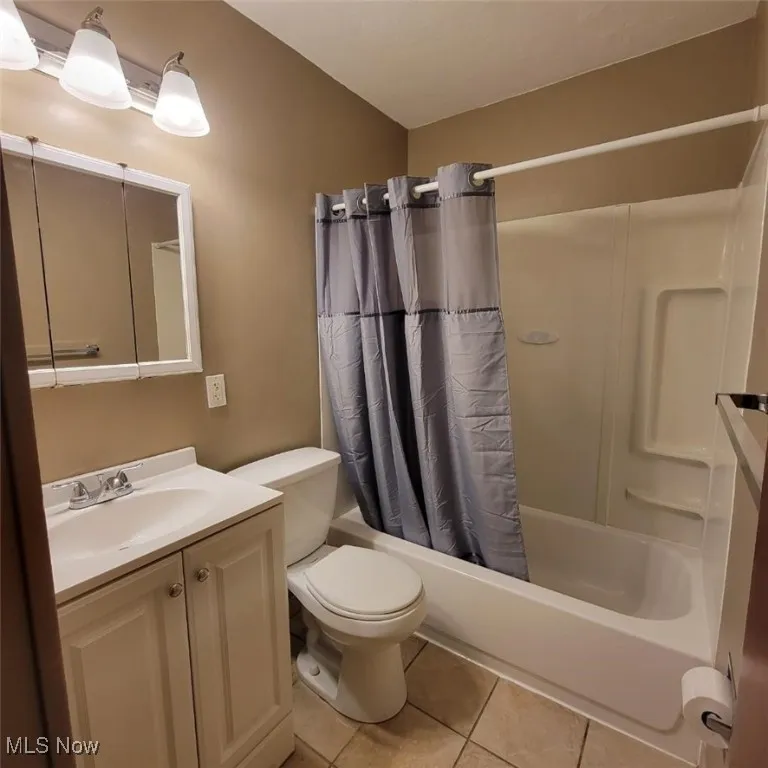 Bathroom with shower / tub combo with curtain, vanity, and light tile patterned floors