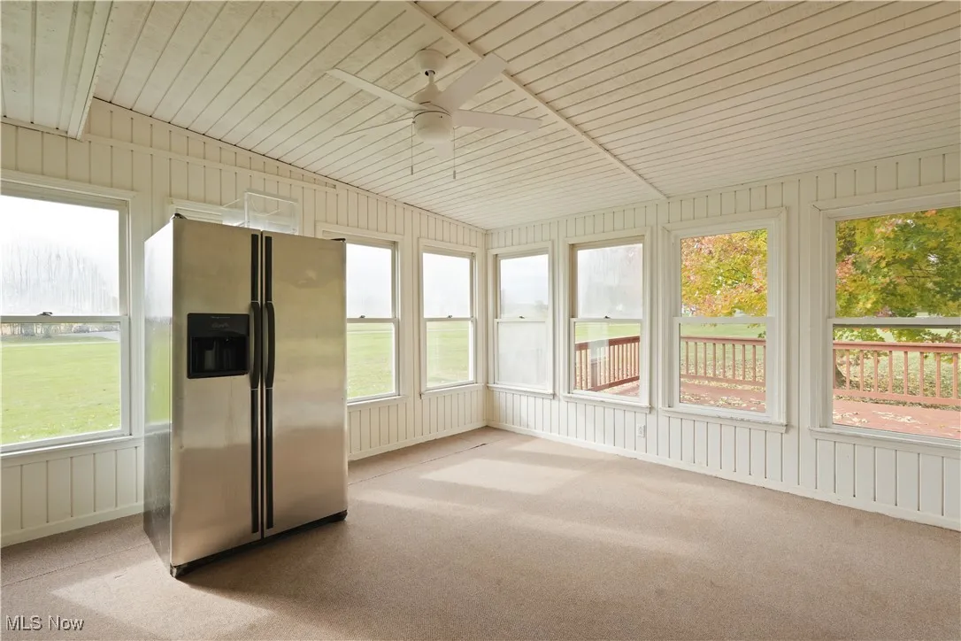 Unfurnished sunroom featuring ceiling fan, carpet floors, and wood ceiling