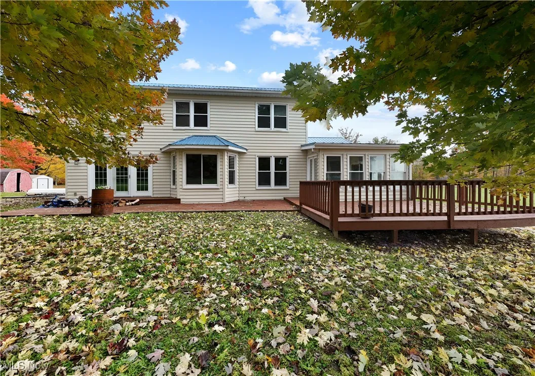 Back of house with a wooden deck, a yard, and an outbuilding