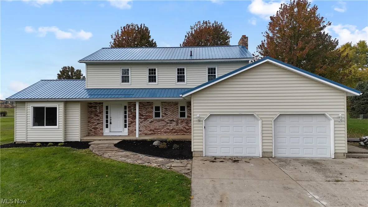 Traditional home with covered porch, a metal roof, a front lawn, concrete driveway, and a garage