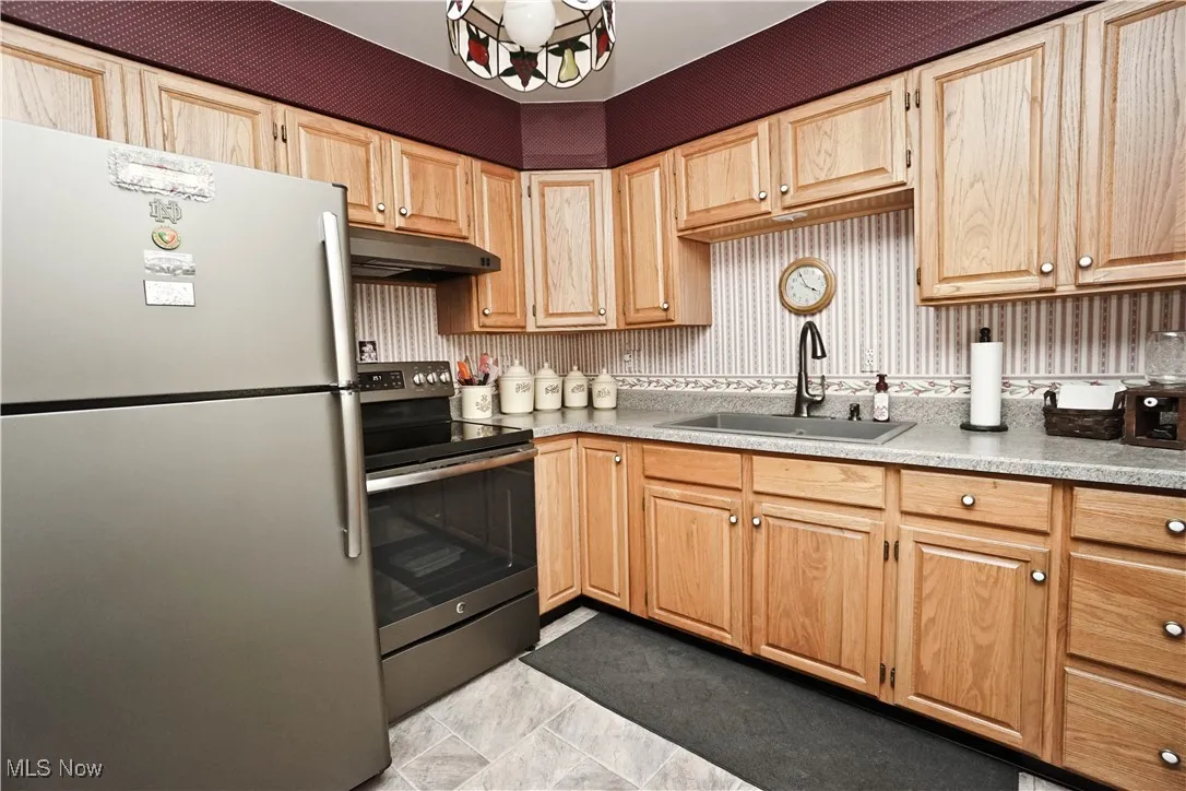 Kitchen featuring appliances with stainless steel finishes, light countertops, light brown cabinets, and under cabinet range hood