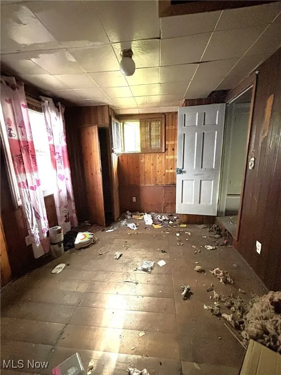 Unfurnished room featuring wood walls and a paneled ceiling