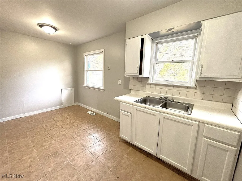 Kitchen with backsplash, light countertops, and white cabinets