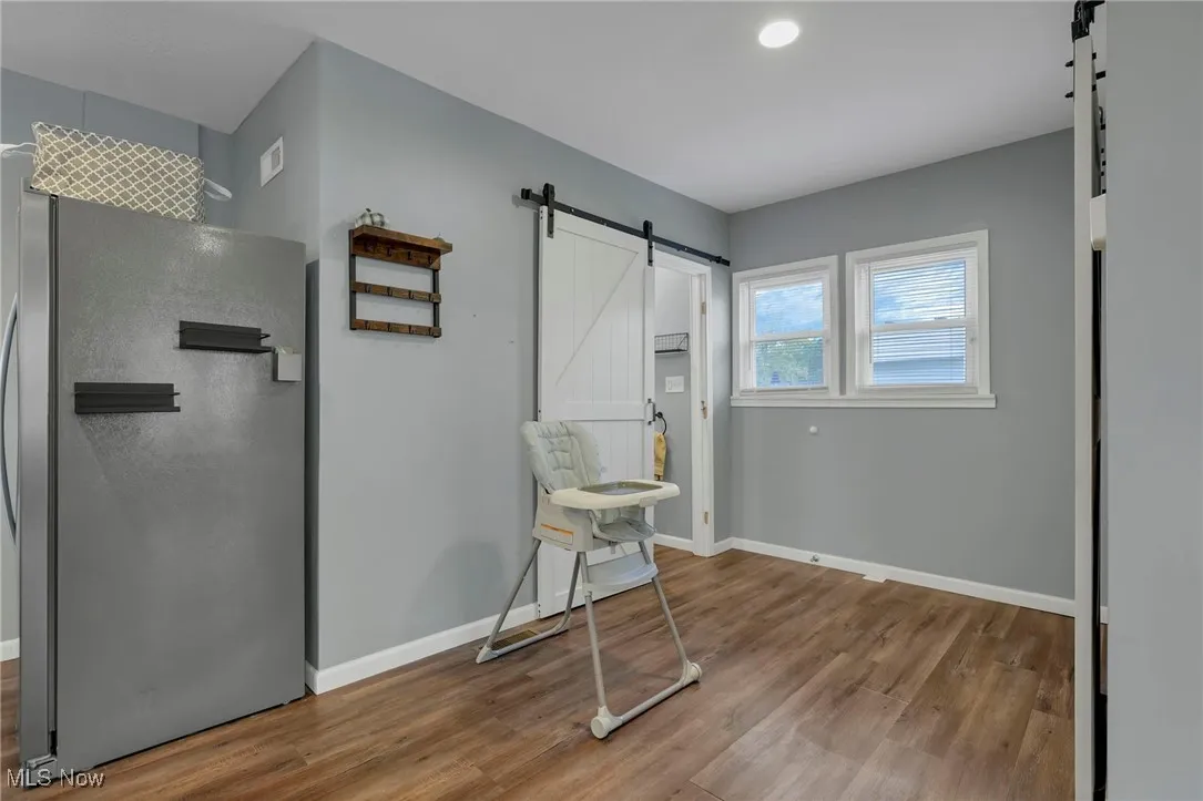 Sitting room featuring a barn door, light wood-style flooring, and recessed lighting
