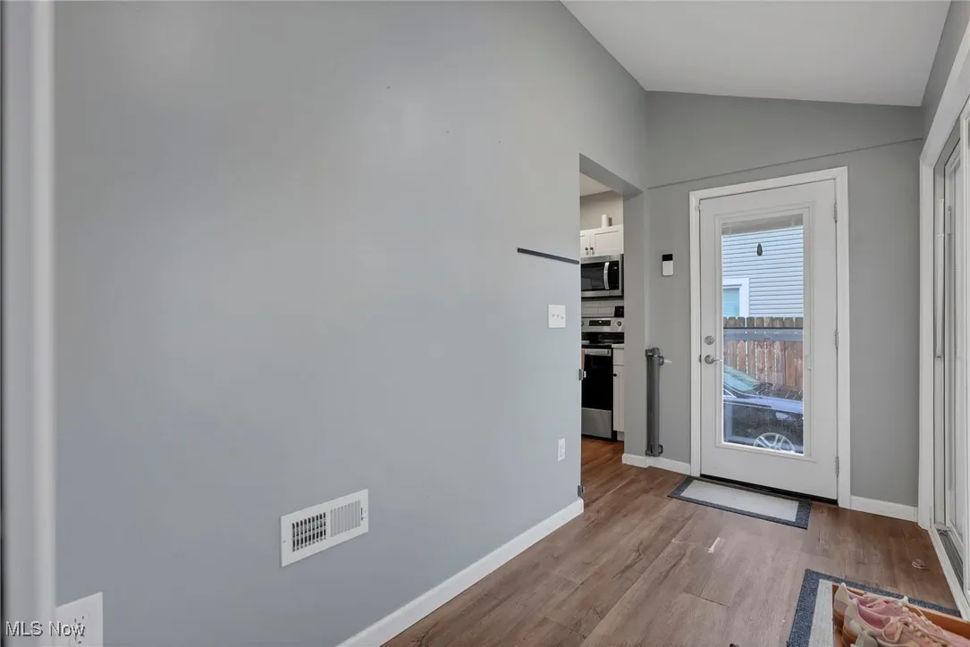 Doorway to outside with wood finished floors and lofted ceiling