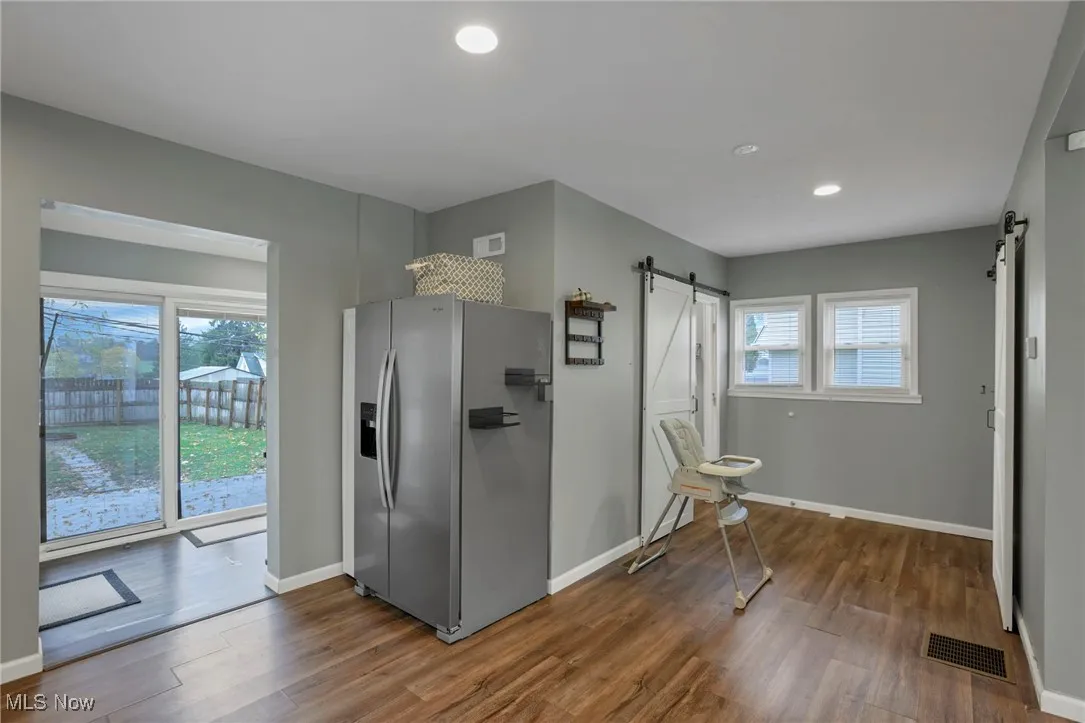 Kitchen featuring a barn door, stainless steel refrigerator with ice dispenser, dark wood-style floors, and recessed lighting