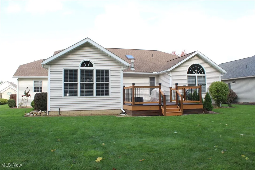 Rear view of house featuring a wooden deck and a yard