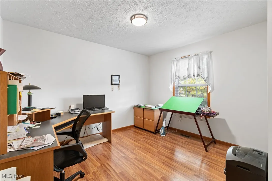 Office with light wood-style flooring and a textured ceiling