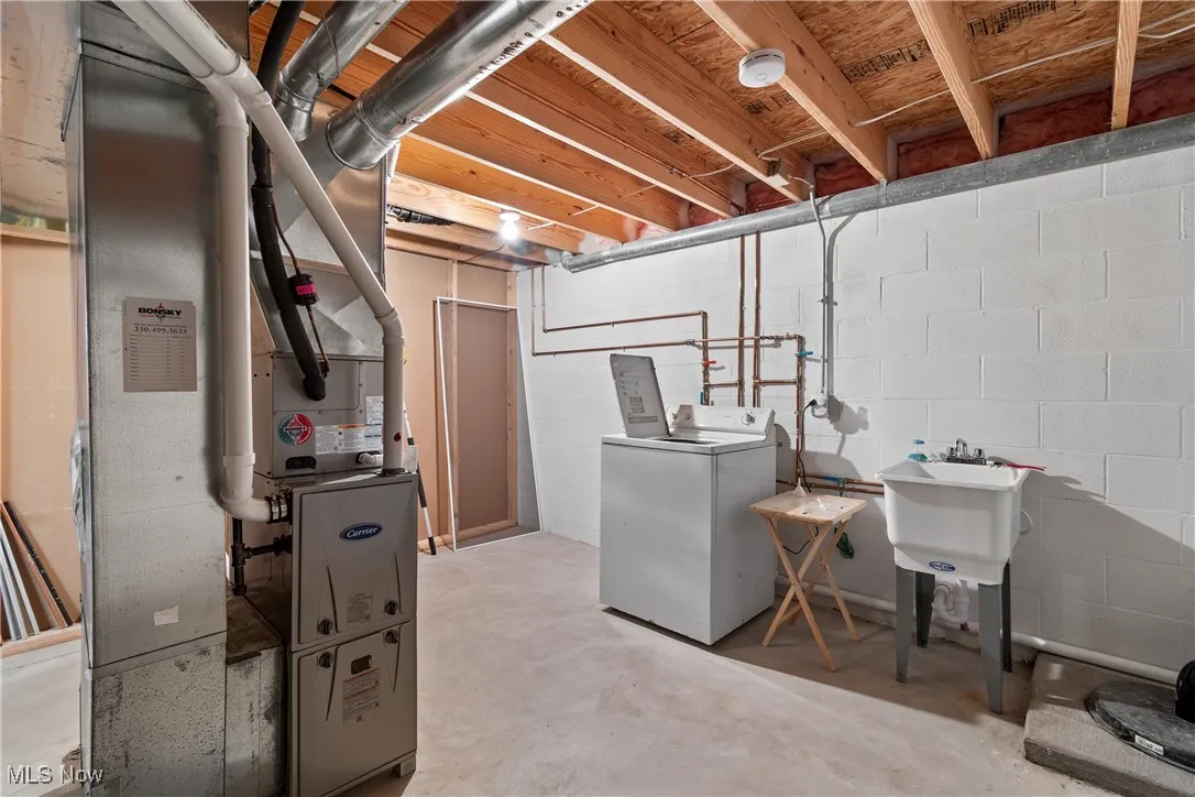 Unfinished basement featuring washer / dryer and heating unit