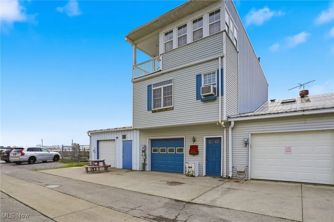 View of front of house with concrete driveway and a balcony