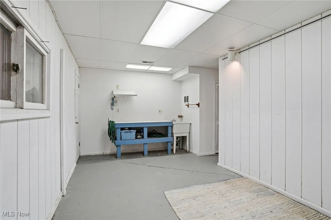 Below grade area featuring a paneled ceiling, a workshop area, and wooden walls