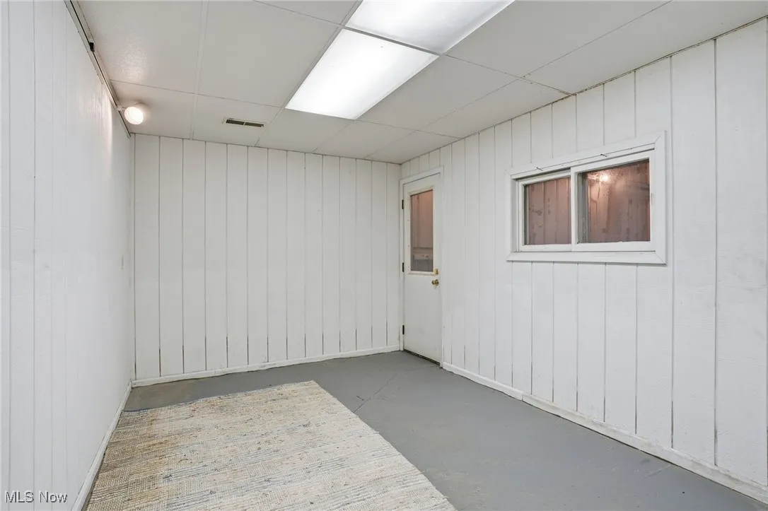 Unfurnished room with wood walls, concrete flooring, and a paneled ceiling