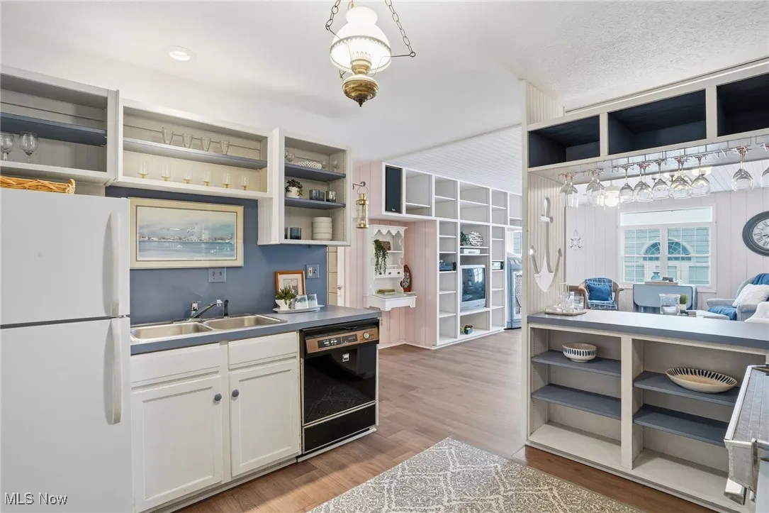 Bar with freestanding refrigerator, open shelves, black dishwasher, light wood finished floors, and white cabinetry