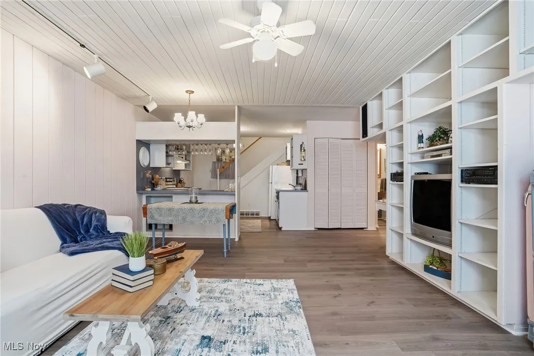 Living room featuring light wood finished floors, rail lighting, ceiling fan, a chandelier, and wooden ceiling