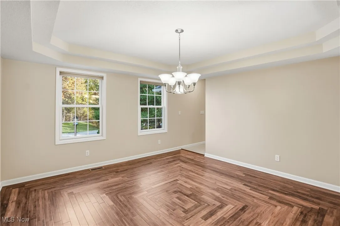 Spare room featuring a tray ceiling and a chandelier