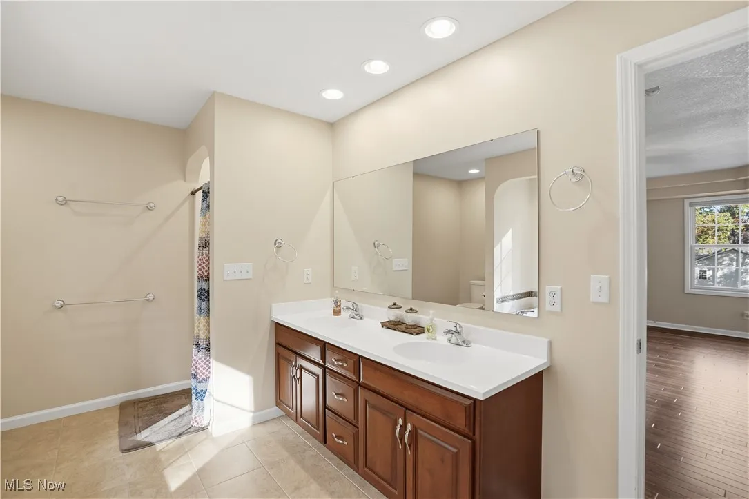 Bathroom with double vanity, curtained shower, recessed lighting, and light tile patterned flooring