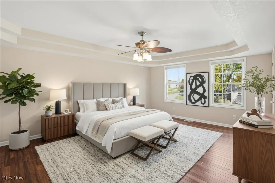 Bedroom with a tray ceiling, dark wood finished floors, and a ceiling fan