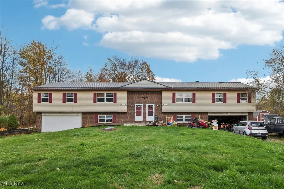 Bi-level home featuring a garage, brick siding, and a front yard