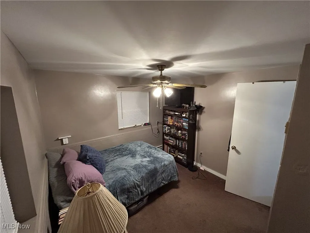 Bedroom with dark colored carpet and ceiling fan