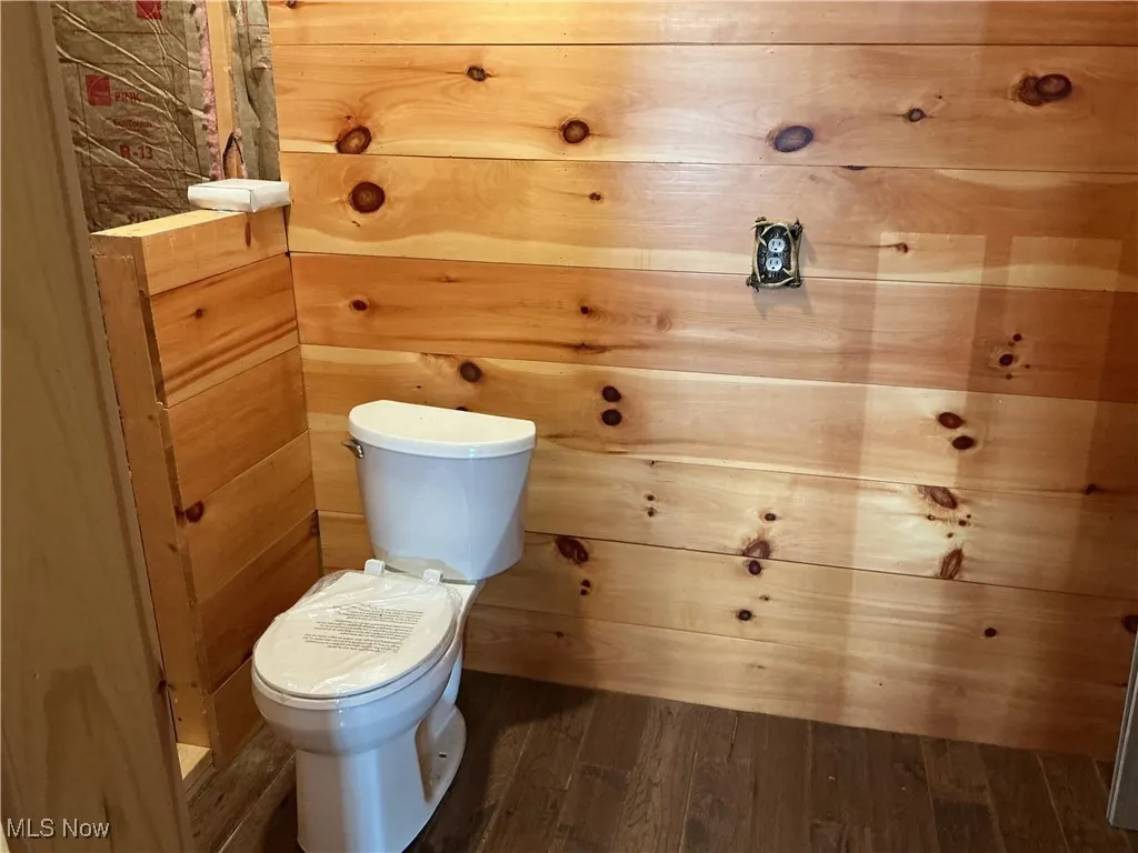 Bathroom with dark wood finished floors and wooden walls