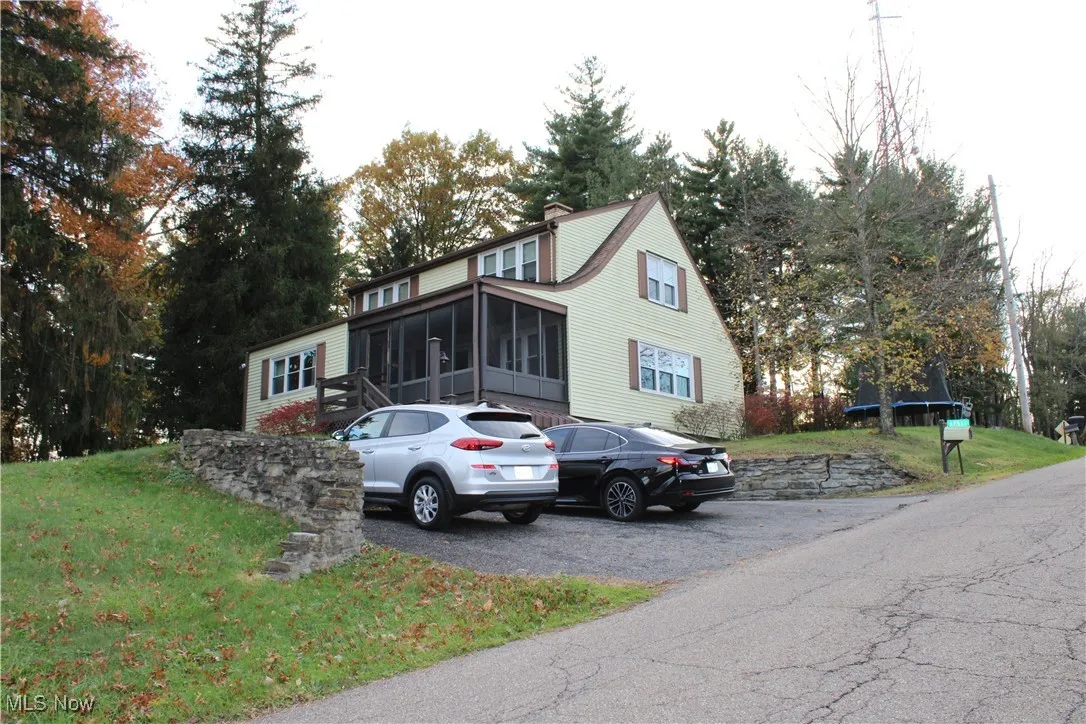 View of front of property featuring a front yard, view of wooded area, and a chimney