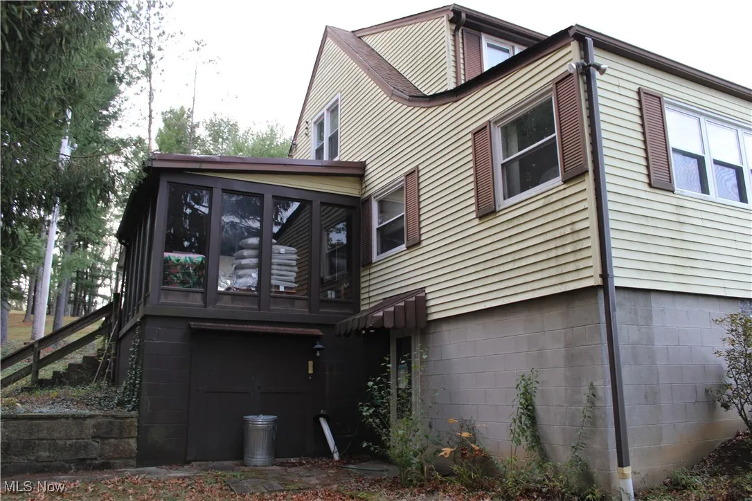 Rear view of house featuring a sunroom and stairway