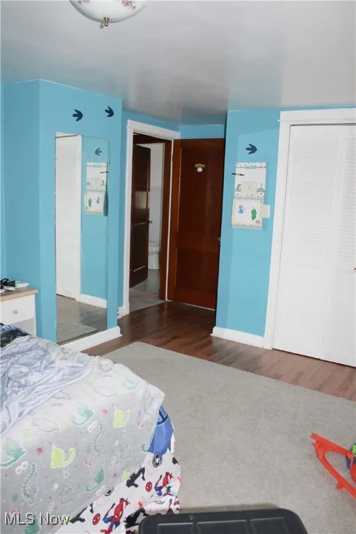 Bedroom with a closet and dark wood-style floors